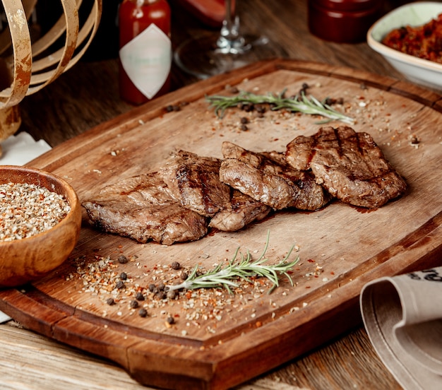 Pedaços de carne fritos com especiarias em uma placa de madeira