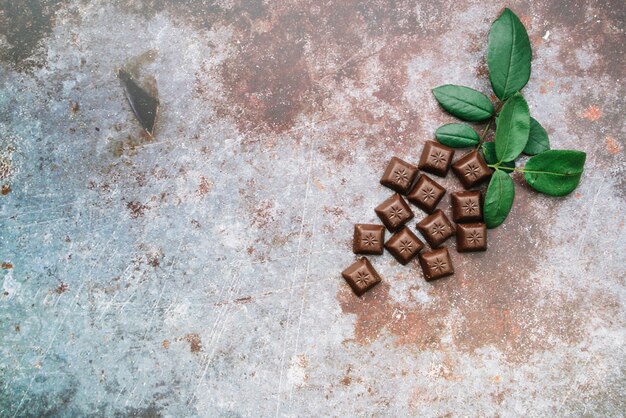 Pedaços de chocolate com folhas sobre fundo rústico grunge