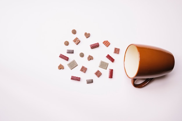 Pedaços de chocolate diferentes com caneca caída no fundo branco