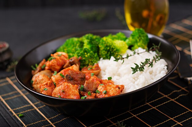 Pedaços de filé de frango com cogumelos cozidos em molho de tomate com brócolis cozido e arroz. Nutrição apropriada. Estilo de vida saudável. Menu dietético.