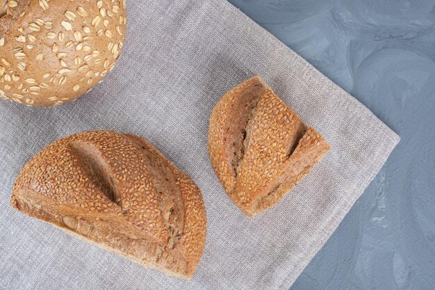 Pedaços de pão fatiados com revestimento de gergelim em uma toalha na mesa de mármore.