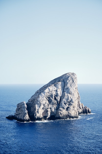 Pedra grande no meio do mar com um céu azul