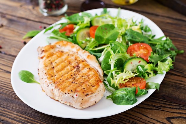 Peito de frango grelhado e salada de legumes frescos - folhas de tomate, pepino e alface. Salada de galinha. Comida saudável.