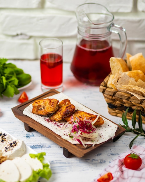 Foto grátis peitos de frango grelhados marinados saudáveis cozidos em um churrasco de verão e servido em lavash com ervas frescas, vinho, pão em uma placa de madeira, close-up vista