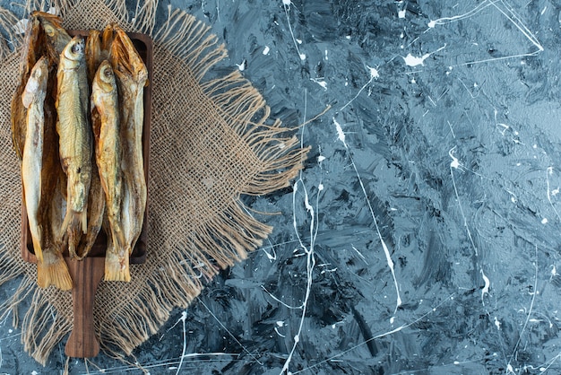 Peixe assado em uma placa na textura, no fundo azul.