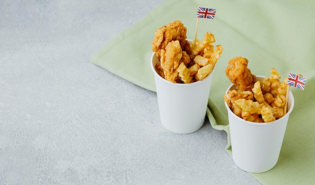 Peixe com batatas fritas em copos de papel com bandeiras da Grã-Bretanha e espaço de cópia