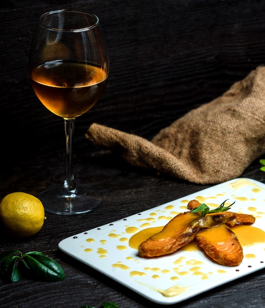 Peixe frito derramado com molho de limão e uma taça de champanhe