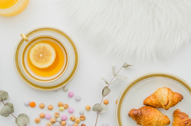 Foto grátis pele; croissant cozido; doces e copo de chá de gengibre limão no fundo branco