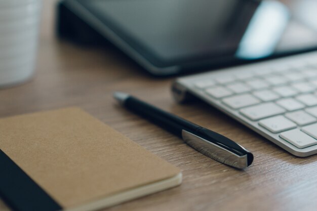 Pen ao lado do teclado sobre a mesa de madeira