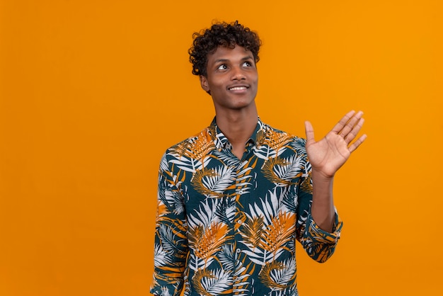 Pensamento feliz jovem bonito com camisa acenando com a mão