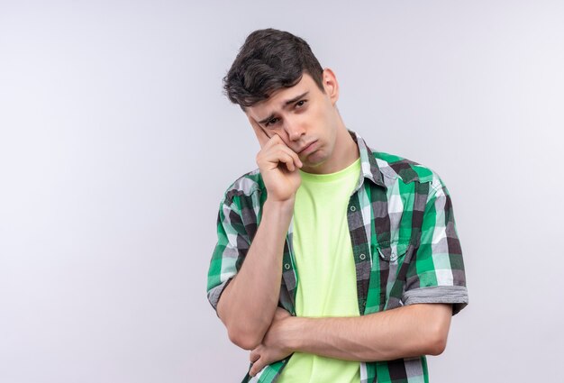 Pensando jovem, caucasiano, vestindo uma camisa verde, colocou a mão na bochecha em um branco isolado