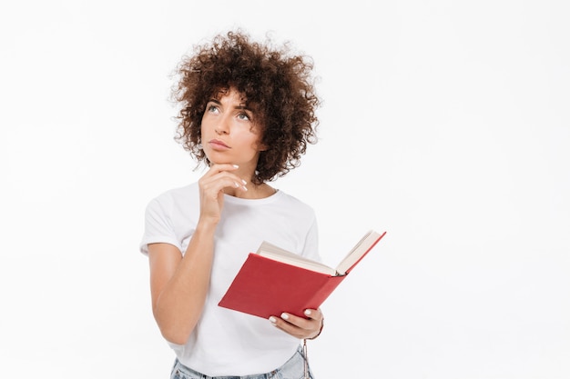 Foto grátis pensativa jovem segurando o livro e desviar o olhar