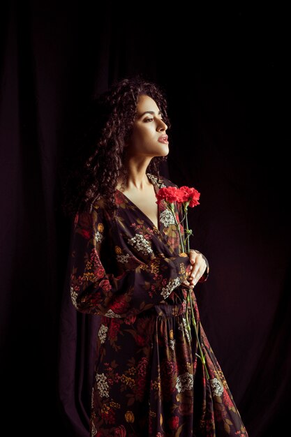 Pensativa mulher negra segurando flores de cravo