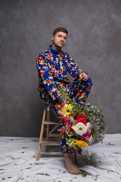 Pensativo, homem jovem, sentando, ligado, madeira, pequeno, escada, segurando, buquê flor, em, mão