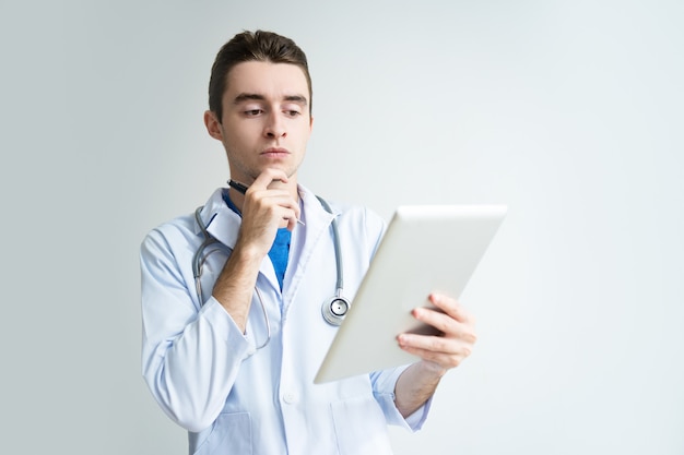 Pensativo jovem médico masculino usando computador tablet
