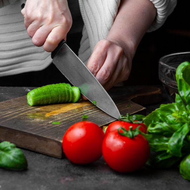 Foto grátis pepino de corte de mulher na mesa