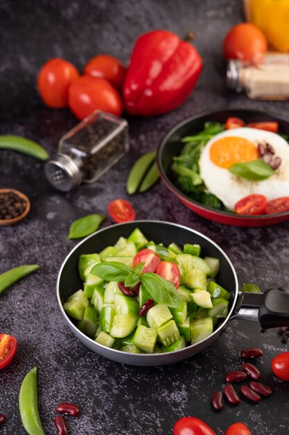 Pepino frito com tomate e feijão vermelho em uma frigideira.