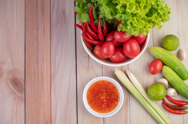 Pepino, limão, tomate, alho, pimenta com molho no chão de madeira.