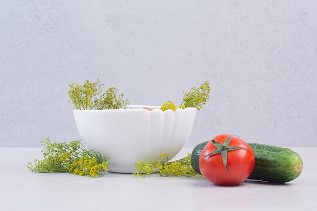 Foto grátis pepinos fatiados e tomates em uma tigela branca com verduras