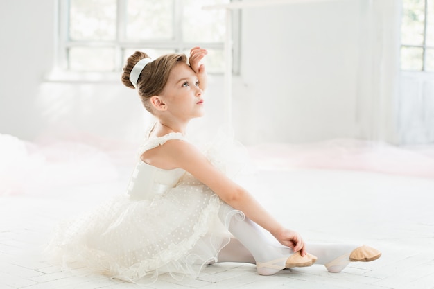 Pequena bailarina com tutu branco na aula na escola de balé