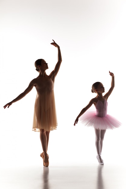 Foto grátis pequena bailarina dançando com professor de balé pessoal no estúdio de dança