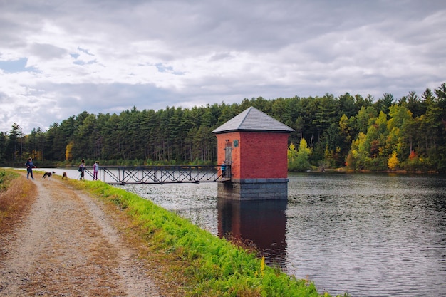 Pequena cabana vermelha construída em um rio e conectada a uma ponte com um cenário natural incrível