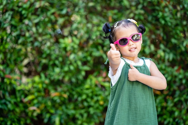 Foto grátis pequena criança asiática posando em um parque com óculos de sol