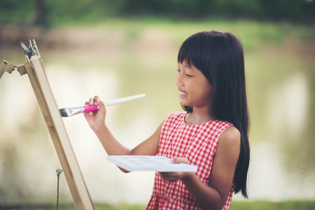 Pequena garota artista pintando imagens no parque