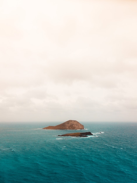 Pequena ilha no oceano sob o céu nublado