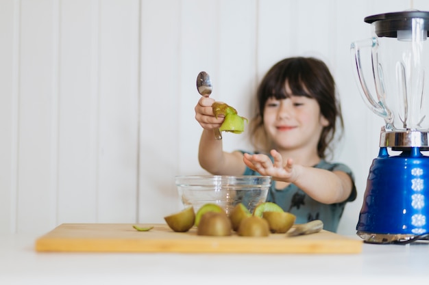 Pequena menina descascando kiwifruit