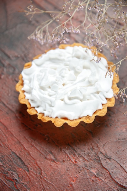 Pequena torta de vista inferior com creme de confeiteiro na mesa vermelha escura