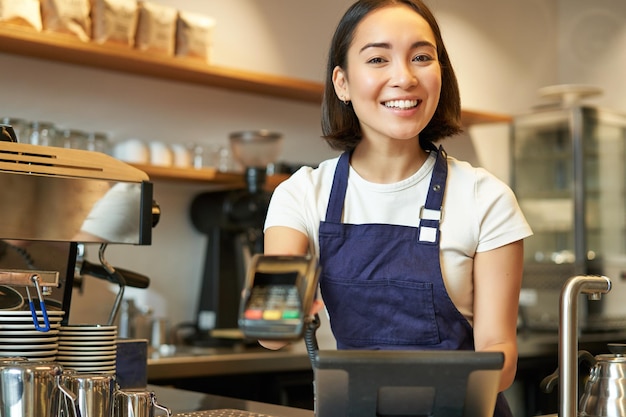 Pequenas empresas e pessoas sorrindo mulher asiática barista trabalhando no café dando carro de crédito terminal pos