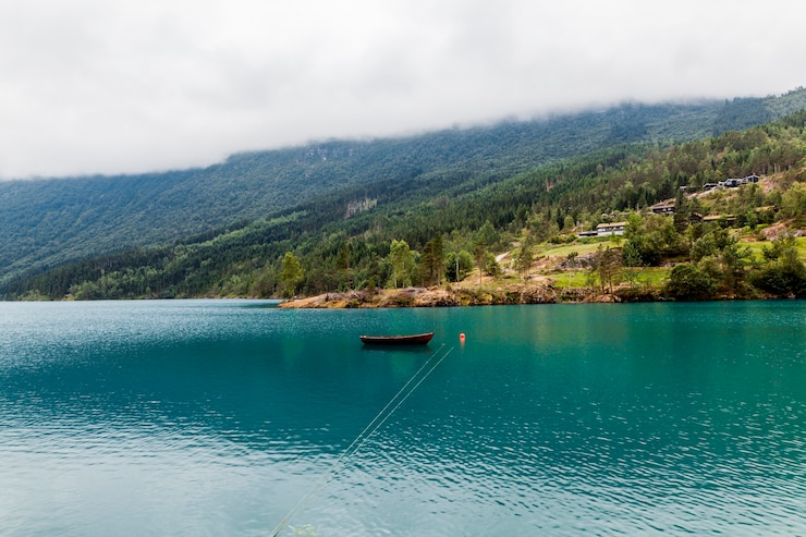 Foto grátis pequeno barco atracado no lago azul calmo com montanha verde