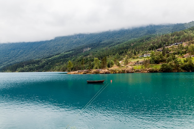 Pequeno barco atracado no lago azul calmo com montanha verde