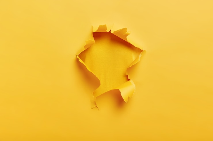 Foto grátis pequeno buraco de papel com lados rasgados em um espaço amarelo para seu texto
