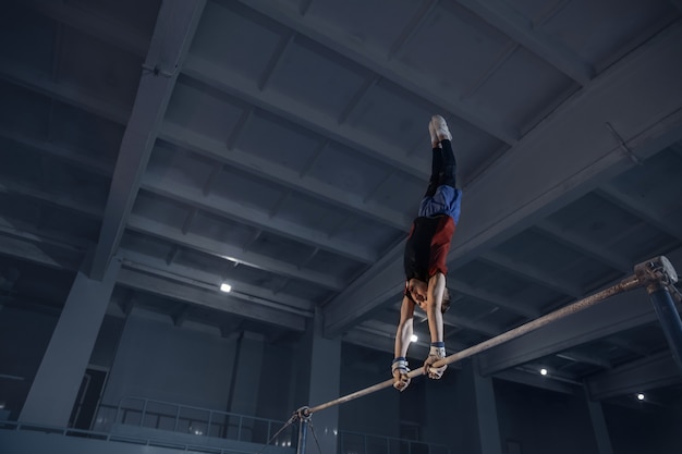 Pequeno ginasta masculino treinando em ginásio flexível e ativo