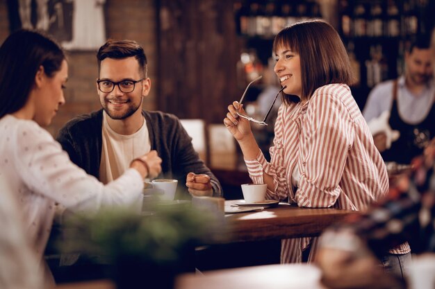 Pequeno grupo de amigos tomando café e se comunicando enquanto está sentado em um café