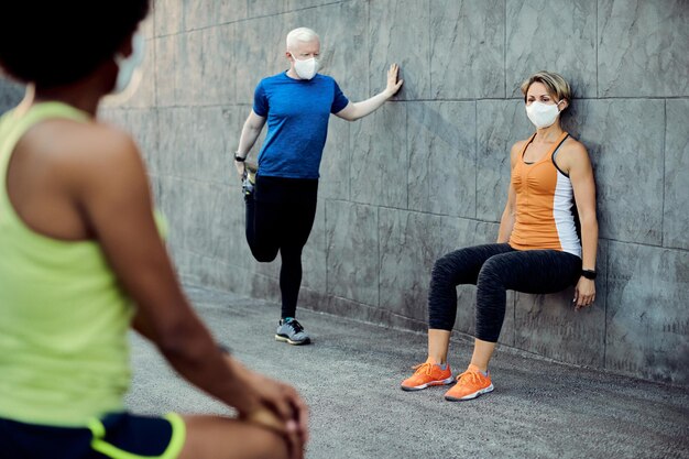 Pequeno grupo de atletas usando máscaras enquanto se aquece ao ar livre