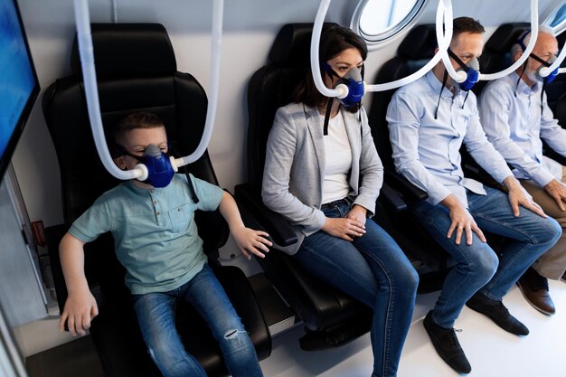 Pequeno grupo de pessoas usando máscaras enquanto faz oxigenoterapia hiperbárica na clínica O foco é na mulher