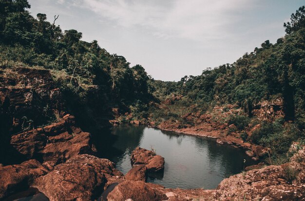 Pequeno lago rodeado por falésias cobertas de árvores e musgo