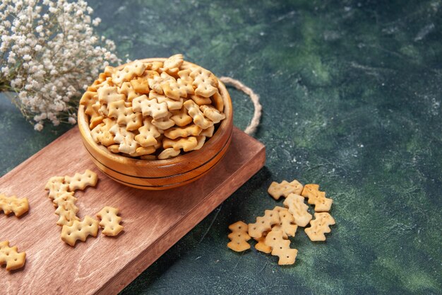 Pequenos biscoitos de frente dentro do prato em um fundo cinza-escuro torresmo salgadinho salgadinho comida cips cor