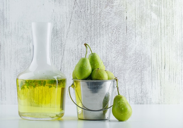 Peras em um mini balde com vista lateral para bebidas à base de plantas em fundo branco e sujo