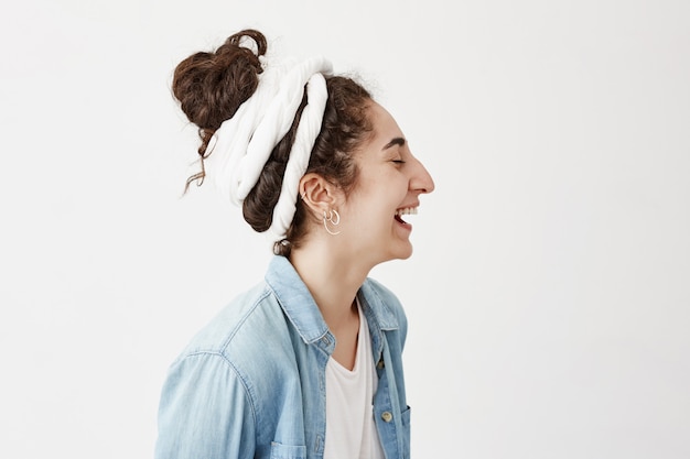 Perfil de garota com cabelos escuros e ondulados em trapos de bom humor, sorrindo e rindo. Linda mulher com um sorriso feliz, sonhando e aproveitando o bom dia. Emoções e expressão facial