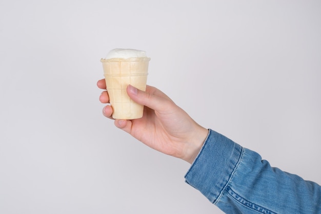 Perfil lateral cortado perto da foto da mão segurando uma saborosa e deliciosa xícara de sorvete isolado em um fundo cinza