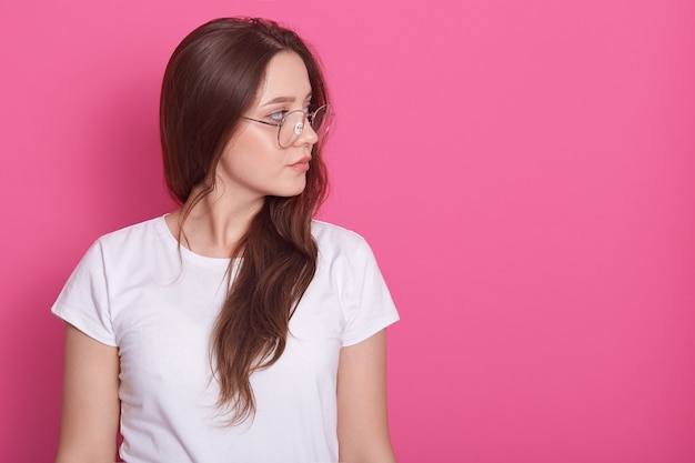 Perfil lateral de retrato de mulher bonita com cabelo comprido, vestido whitr camiseta casual e óculos, olhando de lado