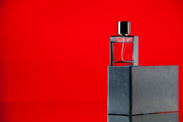 Foto grátis perfume caro de vista frontal como um presente em uma mesa vermelha