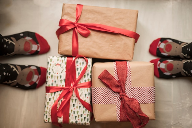 Pernas da pessoa em meias de Natal perto de caixas de presentes