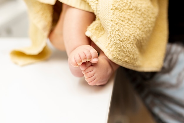 Pernas de bebê close-up com toalha amarela