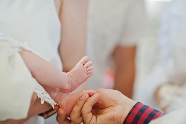 Pernas de bebê recém-nascido na cerimônia de batismo na igreja