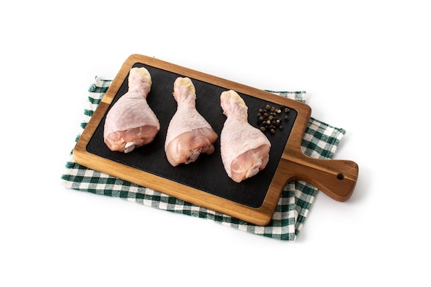 Pernas de carne de frango cru na tábua isolada no fundo branco